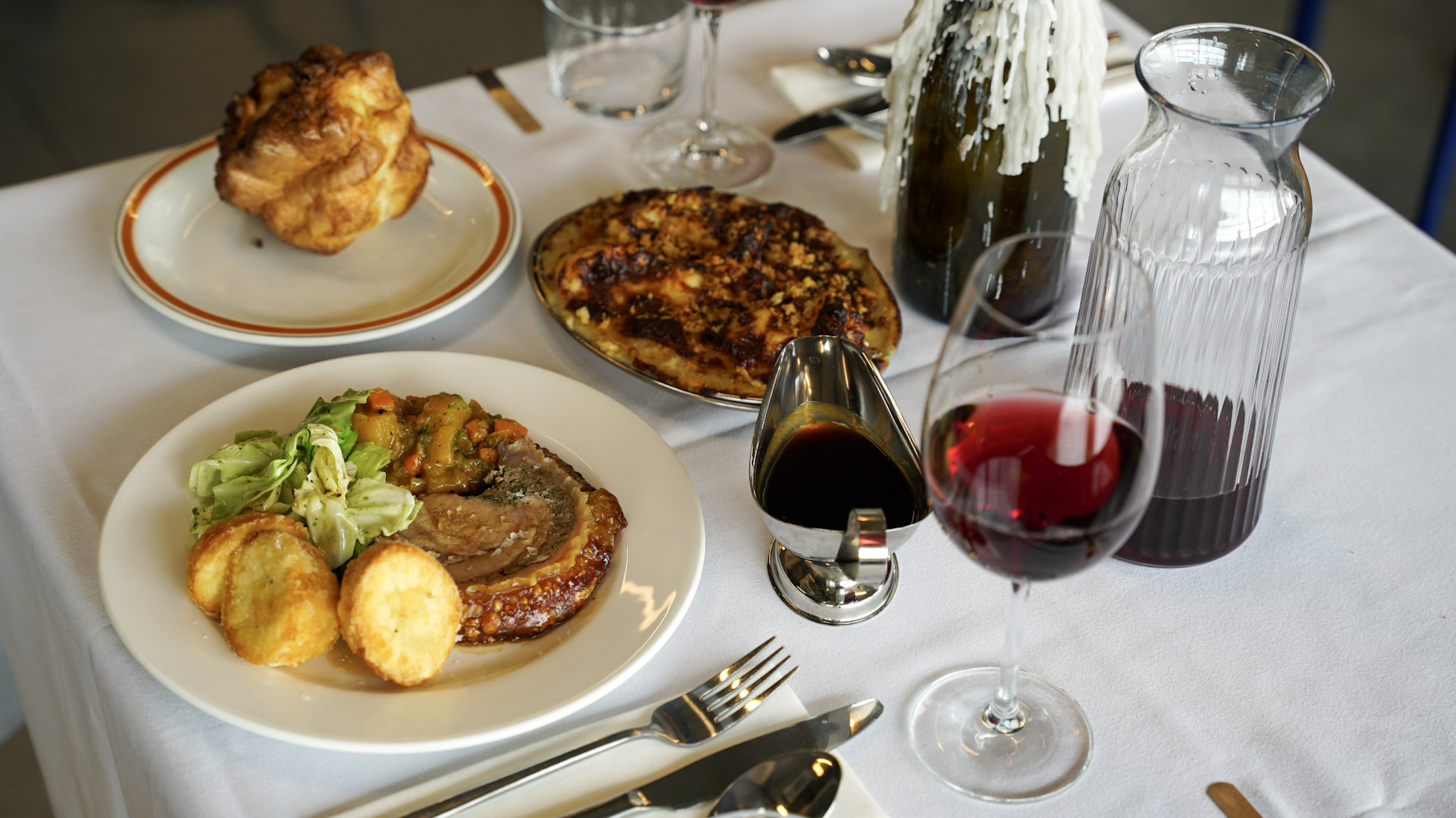 A Sunday table: roast pork, a Yorkshire pudding, cauliflower cheese and red wine